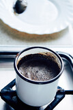 Fototapeta Tęcza - Fresh natural brewed coffee on the gas stove top. in an iron mug