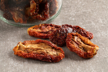 Wall Mural - Heap of dried tomatoes in front of a glass jar close up