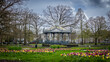 The city park in Apeldoorn called Orange Park, in early spring with blooming multicolored tulips and a pavilion in use  for music and performances in the background, the Netherlands