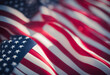 Close-up of the American flag with a shallow depth of field, highlighting the stars and stripes with a soft, blurred background, conveying patriotism and national pride.