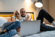 Young couple is engrossed in content on laptop, man and woman entertainment or collaboration, while relaxing in bed.
