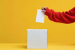 Close-up female hand putting voting card into the ballot box. Vote on free democratic elections or referendum.