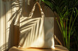 Canvas tote bag on a wooden table bathed in natural sunlight with plant shadows creating a serene atmospher