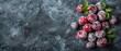   A mound of powdered sugar-coated cherries atop a black background, garnished with green leafy foliage