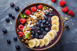 A bowl of fruit with bananas, blueberries, and raspberries. The bowl is on a table with a black background