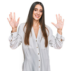 Wall Mural - Young beautiful woman wearing casual white shirt showing and pointing up with fingers number ten while smiling confident and happy.
