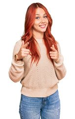 Poster - Young redhead woman wearing casual winter sweater pointing fingers to camera with happy and funny face. good energy and vibes.