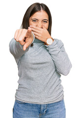 Wall Mural - Young beautiful woman wearing casual turtleneck sweater laughing at you, pointing finger to the camera with hand over mouth, shame expression