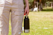 © ADDICTIVE STOCK - Captured in nature, anonymous woman enjoys a sunny getaway, holding a practical and reusable water bottle, ready for a day of adventure outdoors