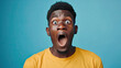 Excited young African American male screaming in shock and amazement on pastel blue background 