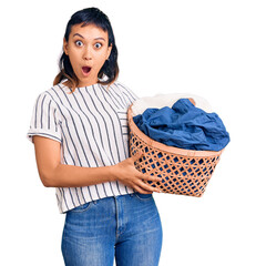 Poster - Young woman holding laundry basket scared and amazed with open mouth for surprise, disbelief face