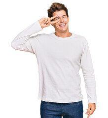 Wall Mural - Handsome caucasian man wearing casual white sweater doing peace symbol with fingers over face, smiling cheerful showing victory