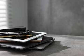 Many different modern gadgets on grey table indoors. Space for text