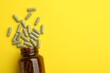 Vitamin pills and bottle on yellow background, top view. Space for text