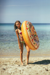 Poster - Young Girl in Bikini Holding Inflatable Donut on Beach