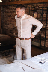 Canvas Print - Young and stylish man wears light suit. Handsome man smile. Background of brick wall