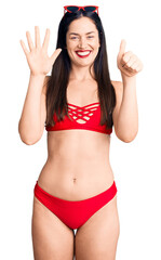 Sticker - Young beautiful caucasian woman wearing bikini showing and pointing up with fingers number six while smiling confident and happy.