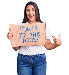 Sticker - Young beautiful woman holding power to the people cardboard banner smiling happy pointing with hand and finger