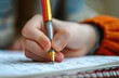 © Natalia - A child holds a pen in his hands and writes in a notebook, close-up
