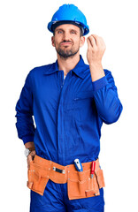 Sticker - Young handsome man wearing worker uniform and hardhat confused and annoyed with open palm showing copy space and pointing finger to forehead. think about it.