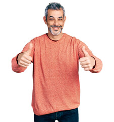 Canvas Print - Middle age hispanic with grey hair wearing casual sweater approving doing positive gesture with hand, thumbs up smiling and happy for success. winner gesture.