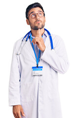 Poster - Young hispanic man wearing doctor uniform and stethoscope thinking concentrated about doubt with finger on chin and looking up wondering