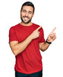 © Krakenimages.com - Young hispanic man wearing casual clothes smiling and looking at the camera pointing with two hands and fingers to the side.