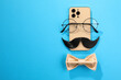 Flat lay composition with artificial moustache and glasses on light blue background, space for text