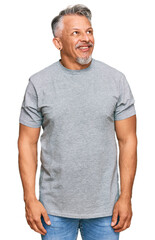 Canvas Print - Middle age grey-haired man wearing casual clothes looking away to side with smile on face, natural expression. laughing confident.