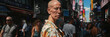 Mature bald woman is walking down a busy city street filled with people and cars