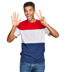 Wall Mural - Young handsome african american man wearing casual clothes showing and pointing up with fingers number seven while smiling confident and happy.