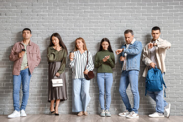 Canvas Print - People waiting in line near grey brick wall