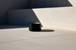 Black circle product podium resting on white surface. Outdoor image of concrete pedestal, form casting bold shadows on courtyard