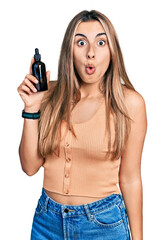 Sticker - Hispanic young woman using night serum scared and amazed with open mouth for surprise, disbelief face