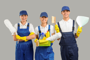 Poster - Workers of cleaning service with supplies on light background