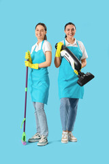 Poster - Female workers of cleaning service with mop and vacuum cleaner on blue background