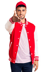 Canvas Print - Young hispanic man wearing baseball uniform smiling friendly offering handshake as greeting and welcoming. successful business.