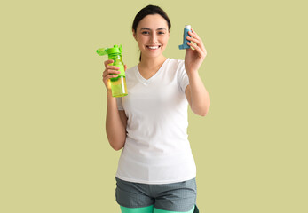 Wall Mural - Sporty young woman with inhaler and water bottle on green background