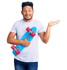 Sticker - Handsome latin american young man holding skate celebrating victory with happy smile and winner expression with raised hands