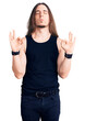 Young adult man with long hair wearing goth style with black clothes relaxed and smiling with eyes closed doing meditation gesture with fingers. yoga concept.