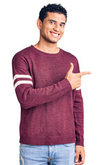 Sticker - Hispanic handsome young man wearing casual clothes cheerful with a smile of face pointing with hand and finger up to the side with happy and natural expression on face