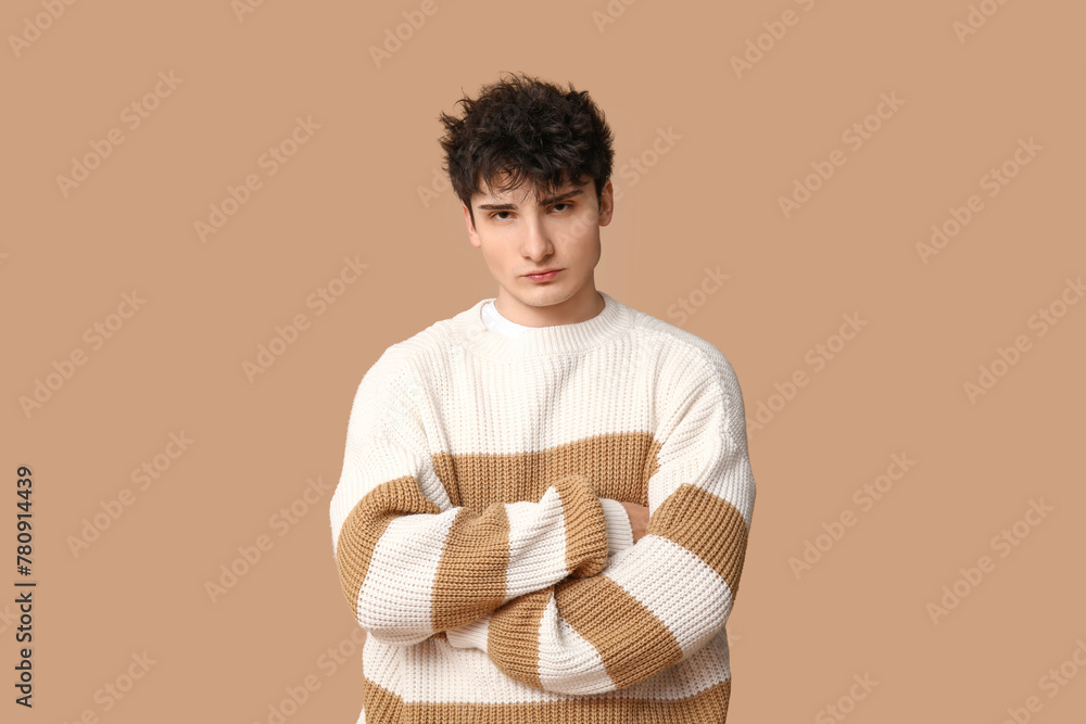 Handsome young man in stylish sweater on brown background