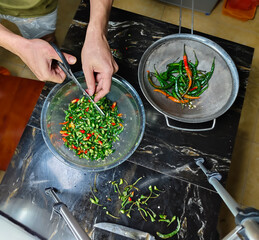 hands cutting chilies with scissors on a man is cutting or chopping chilies using scissors in the ki