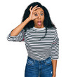 Middle age african american woman wearing casual clothes doing ok gesture shocked with surprised face, eye looking through fingers. unbelieving expression.