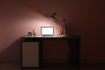 Poster - Table with modern laptop and glowing lamp near pink wall