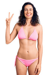 Sticker - Young beautiful hispanic woman wearing bikini showing and pointing up with fingers number two while smiling confident and happy.