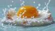   An egg cracks in a pool of water, milk spilling out onto a blue surface