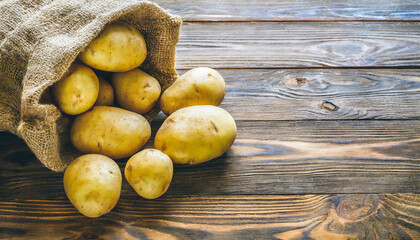 Wall Mural - Raw potato food . Fresh potatoes in an old sack on wooden background. Free place for text. Top view