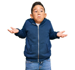 Poster - Little boy hispanic kid wearing casual sporty jacket clueless and confused expression with arms and hands raised. doubt concept.