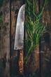 A knife and a sprig of rosemary on a rustic wooden table. Ideal for food or cooking concepts